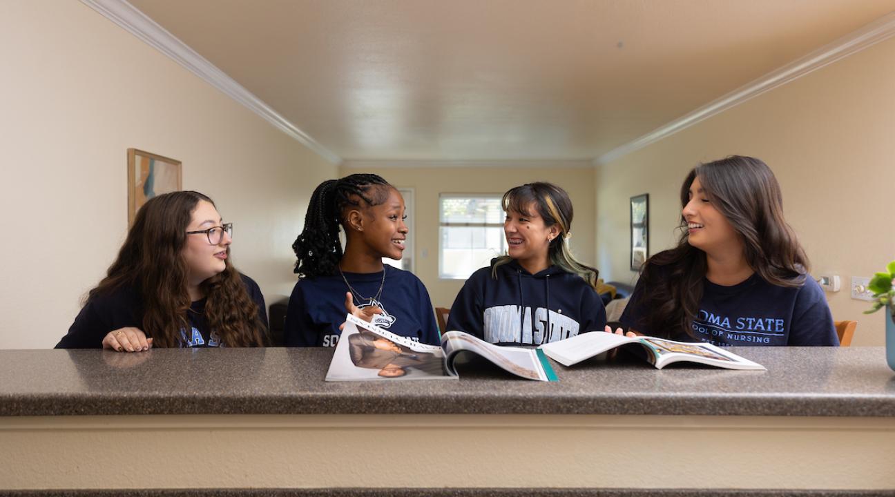 Four students sitting at kitchen counter socializing