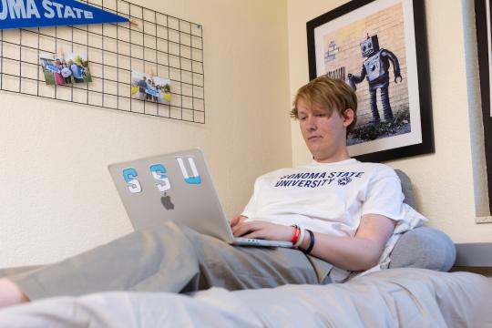 Student Jack sitting on a bed on a laptop