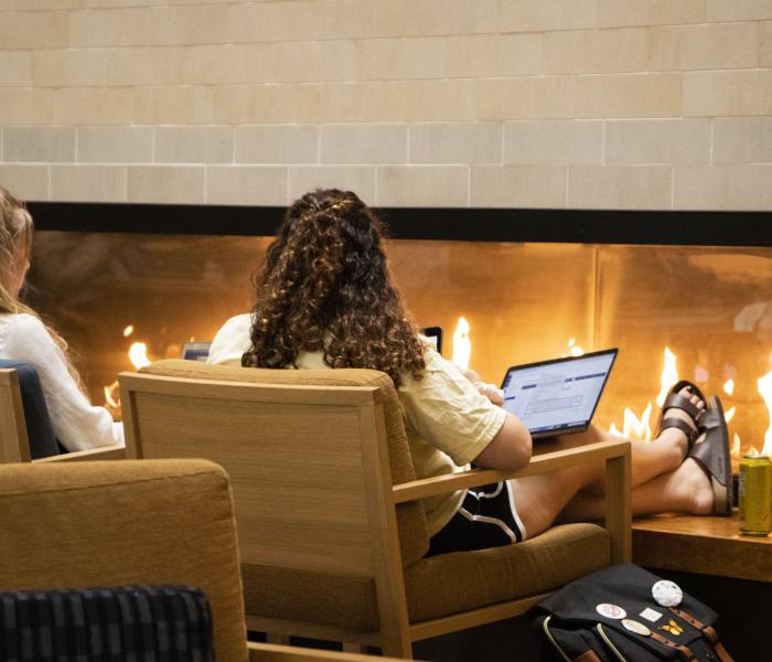 Student on computer in front of fireplace in Student Center 