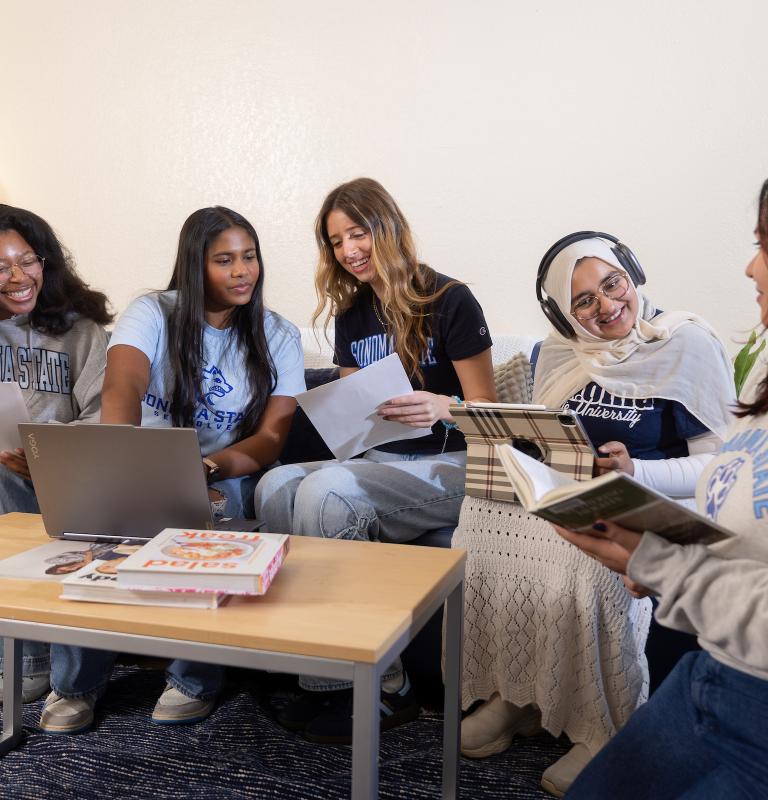 Group of five students in the living room studying