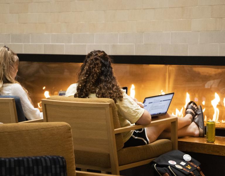 Student on computer in front of fireplace in Student Center 