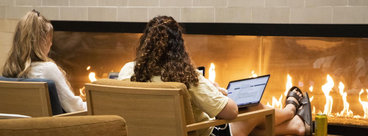 Student on computer in front of fireplace in Student Center 
