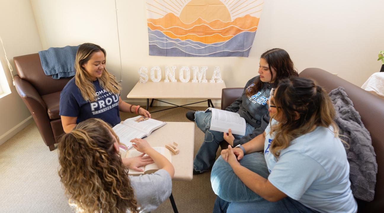 Four students sitting in living room socializing