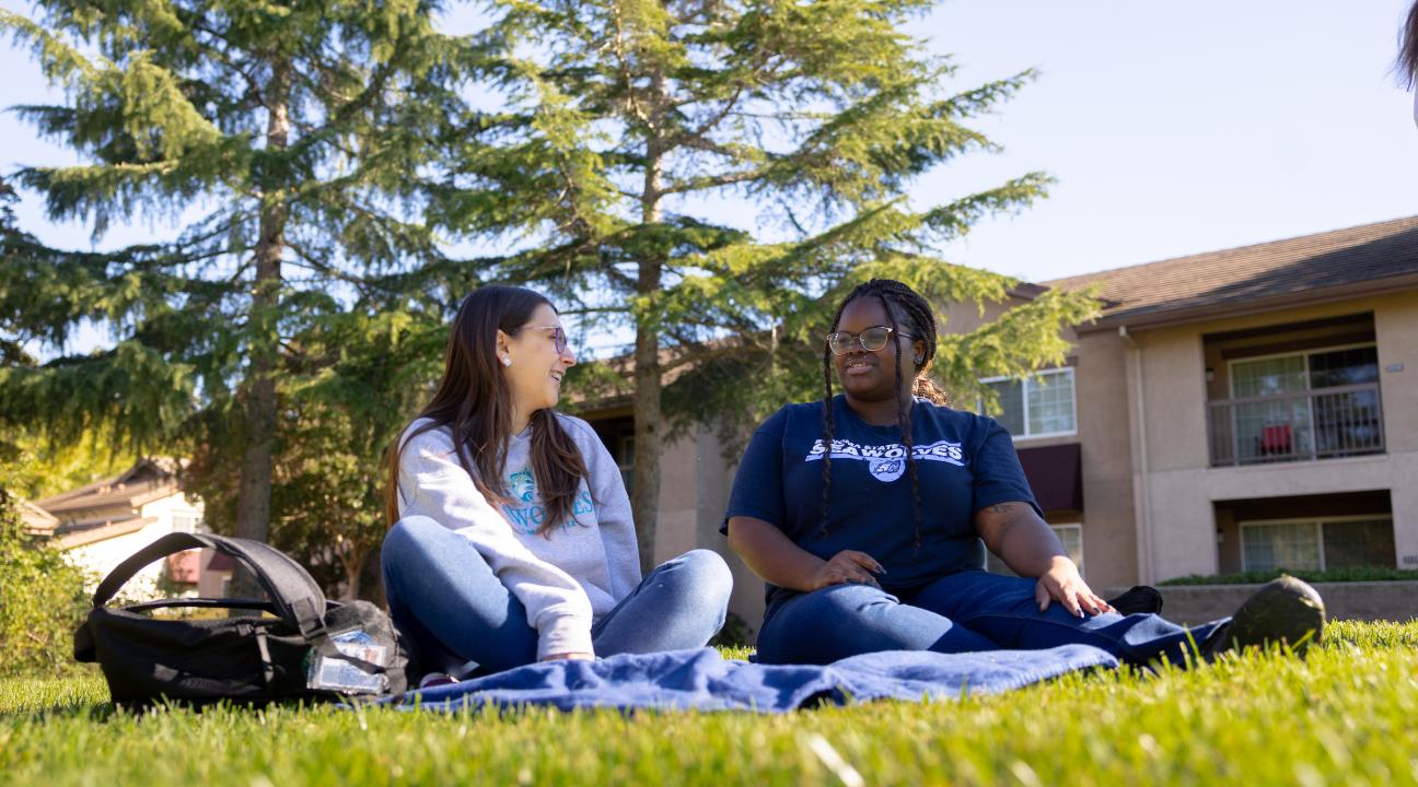 Two students sitting on the lawn socializing