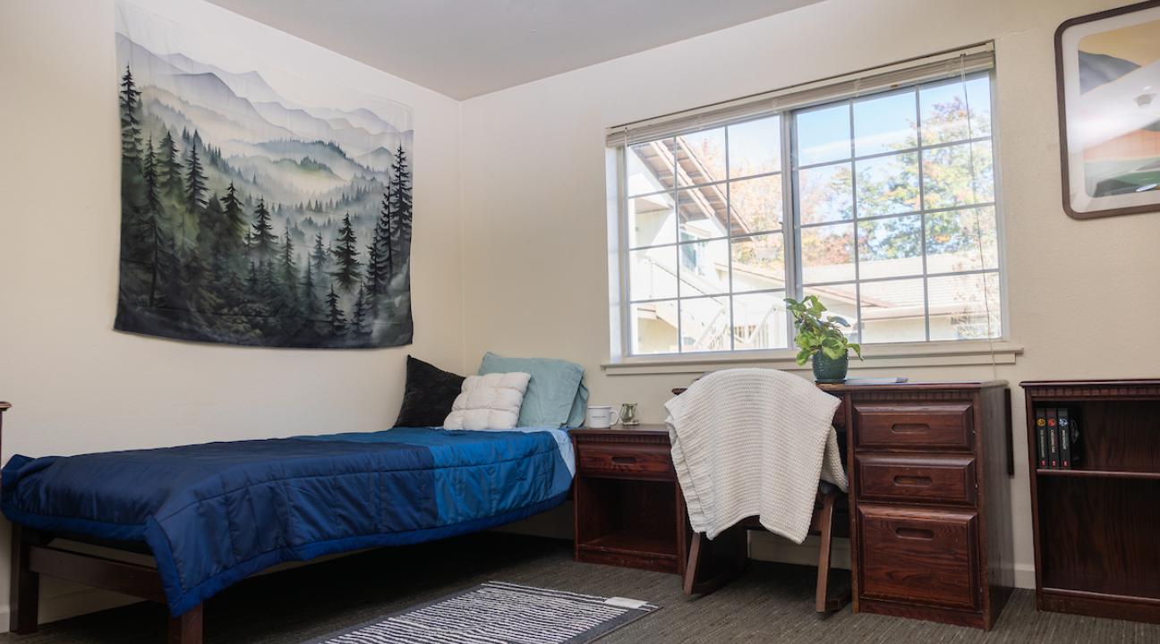 Dorm bedroom with bed, desk and chair