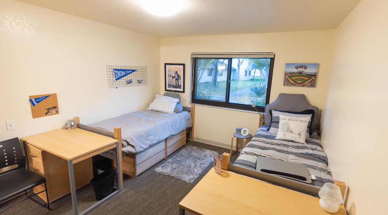 Dorm room with two beds and a desk