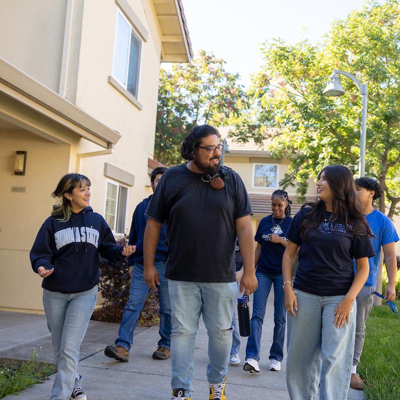 Group of students walking outside housing village and talking
