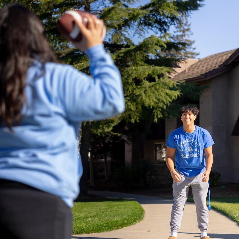 Kent standing waiting for a student to throw a football his way