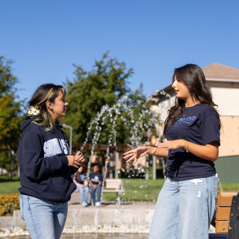 Two people standing next to a fountain talking