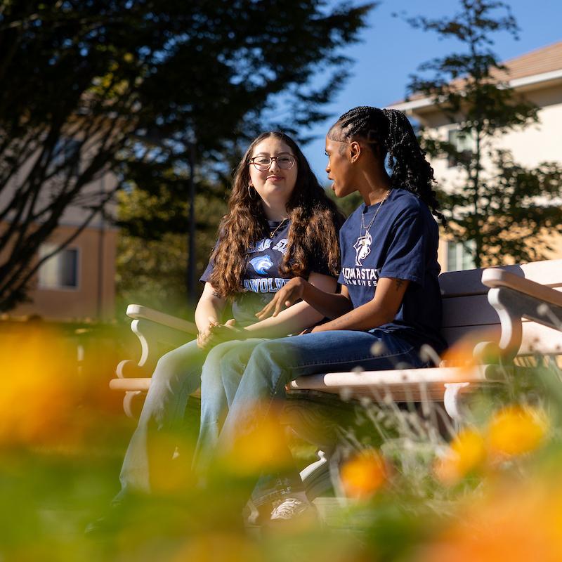 Two students sitting on a bench talking