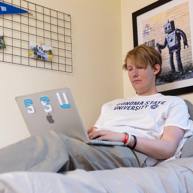 Student Jack sitting on a bed on a laptop