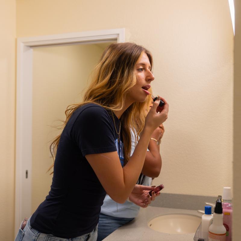 Savannah putting on lipstick in front of a mirror