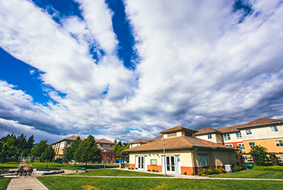 a blue and cloudy sky, a campus building, green grass
