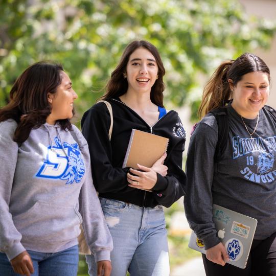 three students walking holding books