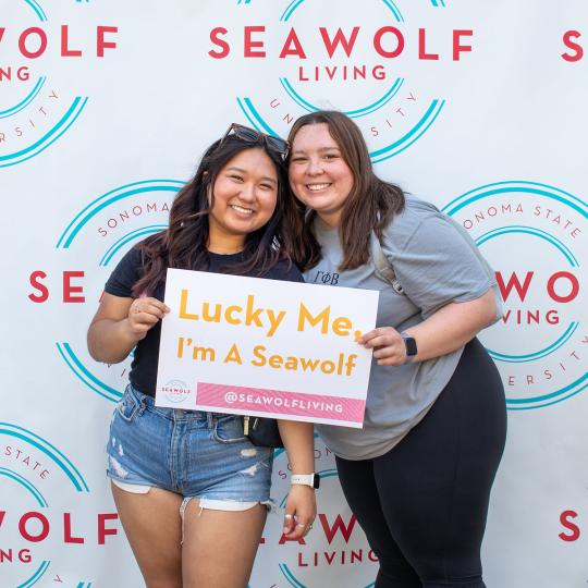 two new students holding up a sign that says "lucky me, i am a seawolf"