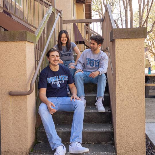 three students sitting on the front steps of housing