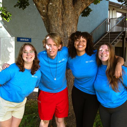 four student RAs wearing blue shirts and smiling