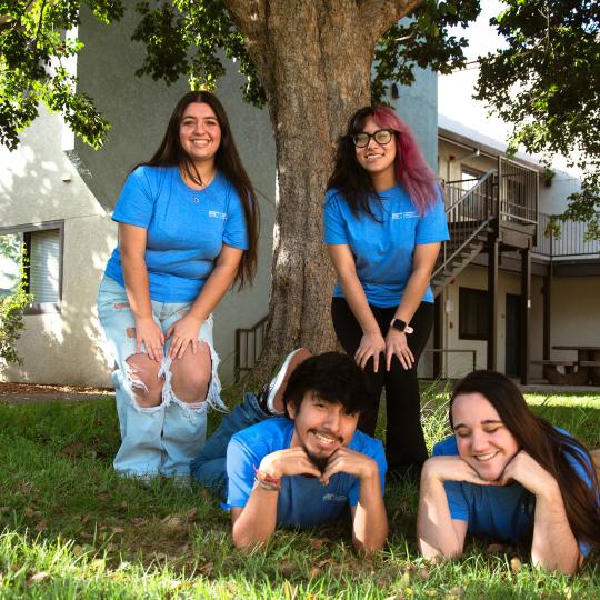 four RAs wearing blue shirts posing together on a lawn