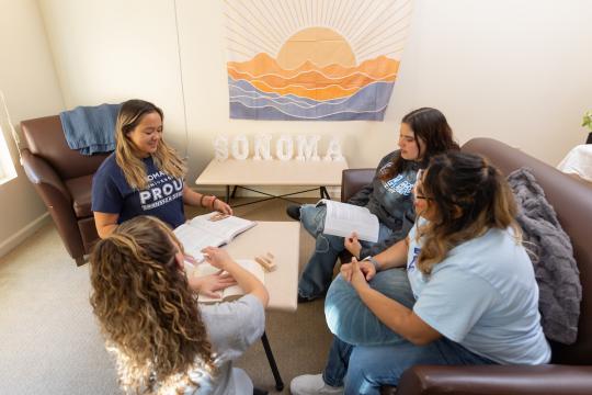 Four students sitting in living room socializing