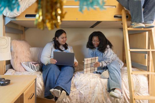 Two students sitting on their bed studying