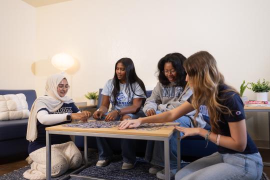 Students in dorm doing a puzzle 