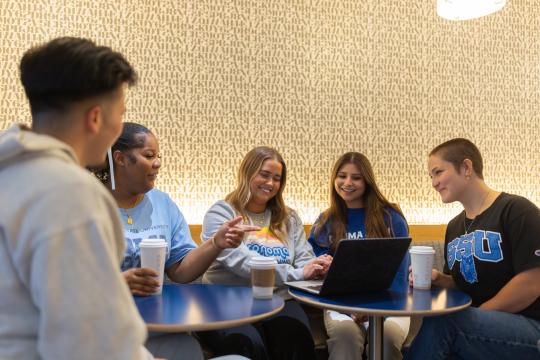 Students looking at a laptop in a coffee shop